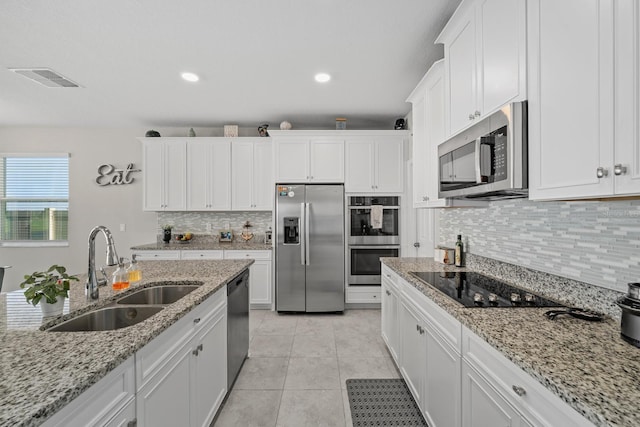 kitchen featuring white cabinetry, appliances with stainless steel finishes, light tile patterned flooring, light stone counters, and sink