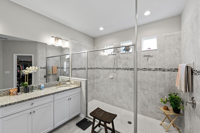 bathroom featuring tile patterned flooring, a tile shower, and vanity