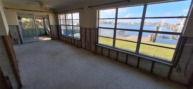 unfurnished sunroom with a water view and ceiling fan