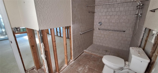 bathroom with toilet, tile patterned floors, and tiled shower