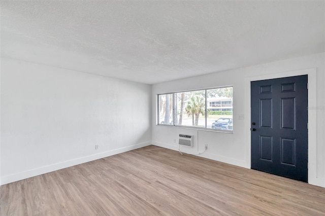 entrance foyer with a textured ceiling, light hardwood / wood-style floors, and a wall mounted air conditioner