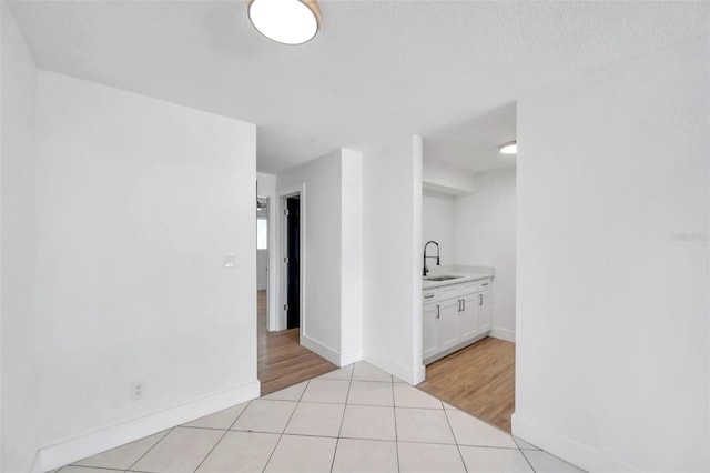 hallway featuring a textured ceiling, light wood-type flooring, and sink