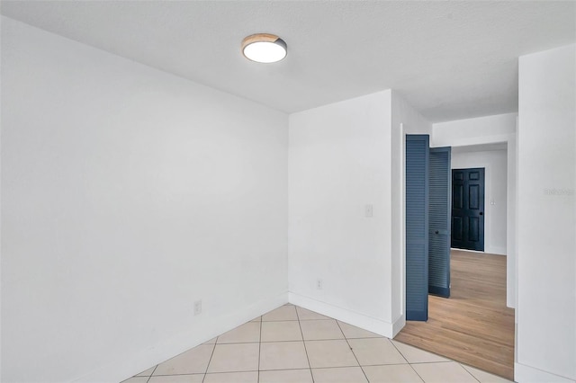 empty room with a textured ceiling and light hardwood / wood-style flooring