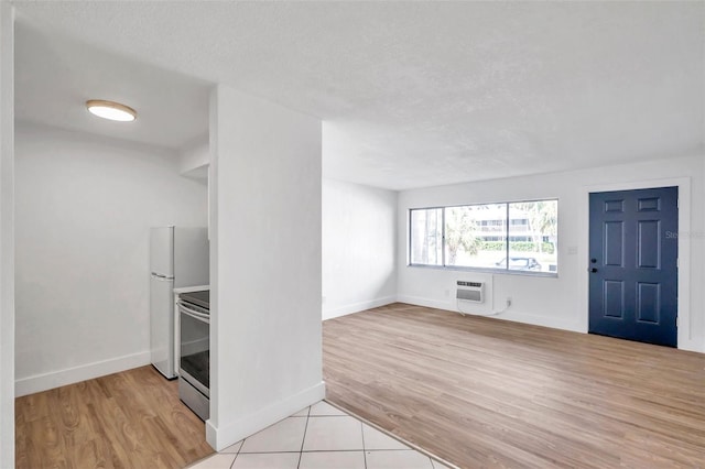 interior space featuring a wall mounted air conditioner, light wood-type flooring, and a textured ceiling