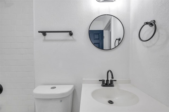 bathroom featuring tiled shower, sink, and toilet