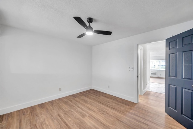 spare room with a wall mounted AC, ceiling fan, a textured ceiling, and light wood-type flooring