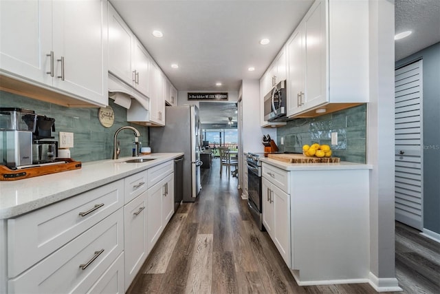 kitchen with tasteful backsplash, stainless steel appliances, white cabinetry, sink, and dark wood-type flooring