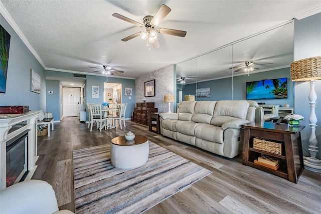 living room featuring a fireplace, hardwood / wood-style flooring, a textured ceiling, and ornamental molding