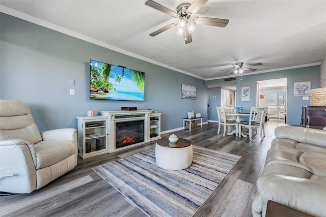 living room with dark wood-type flooring, ceiling fan, a textured ceiling, and crown molding