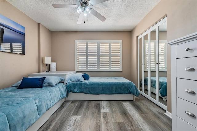 bedroom featuring a closet, hardwood / wood-style floors, ceiling fan, and a textured ceiling