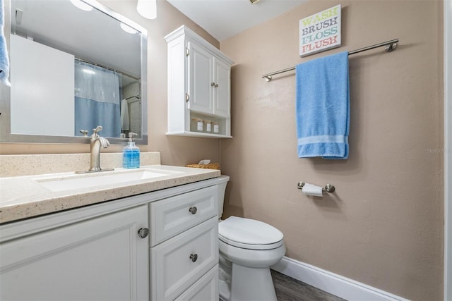 bathroom featuring toilet, vanity, a shower with shower curtain, and hardwood / wood-style flooring