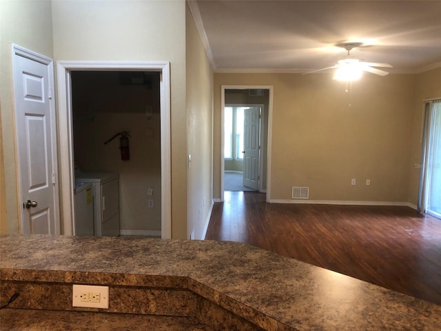 corridor featuring ornamental molding, dark wood-type flooring, and washer and clothes dryer