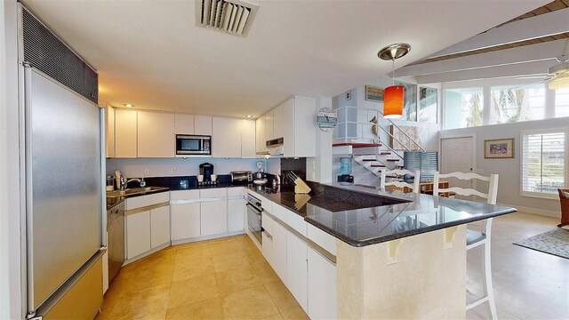 kitchen with a peninsula, visible vents, and white cabinets