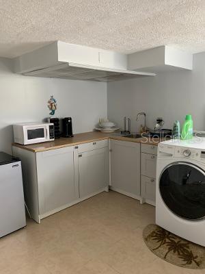 washroom featuring light floors, cabinet space, a sink, and washer / dryer