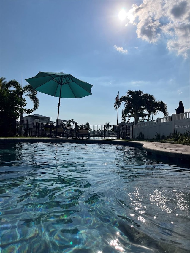 community pool featuring a water view and fence