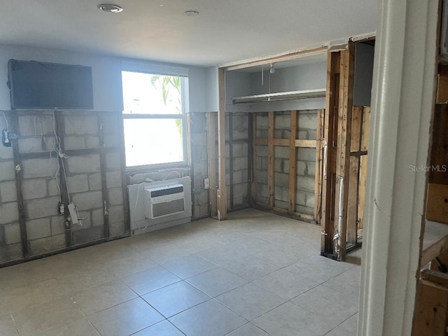 empty room featuring a wall unit AC and light tile patterned floors