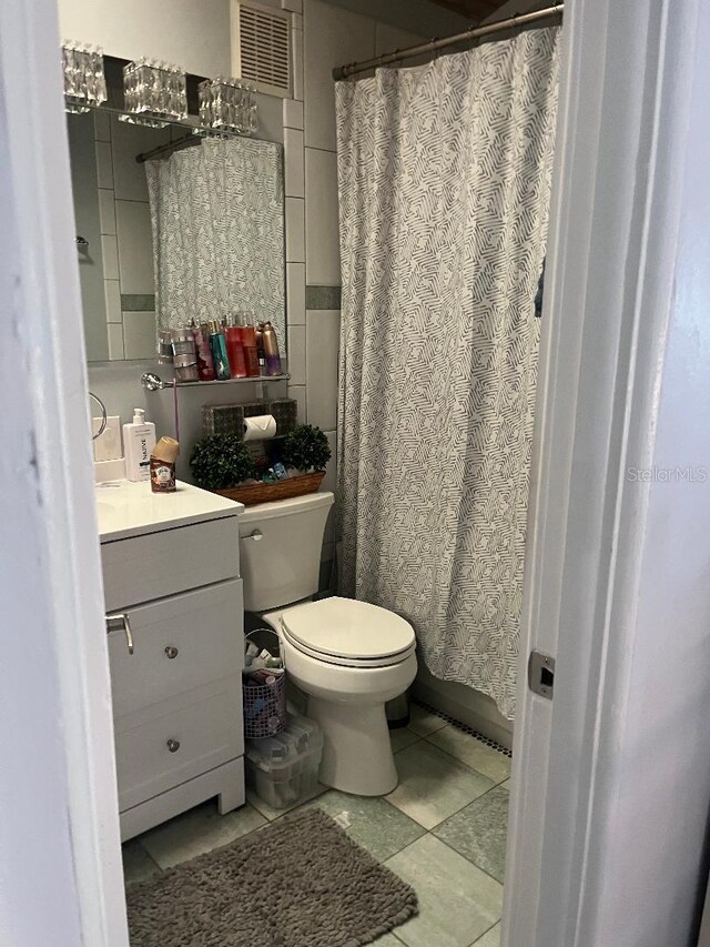 full bathroom with tile walls, visible vents, vanity, and toilet