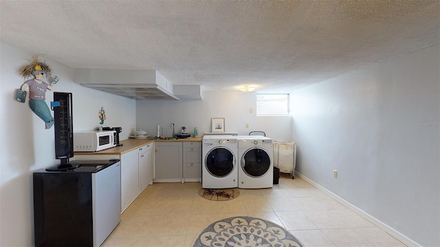 laundry area with a textured ceiling, laundry area, a sink, baseboards, and washer and dryer