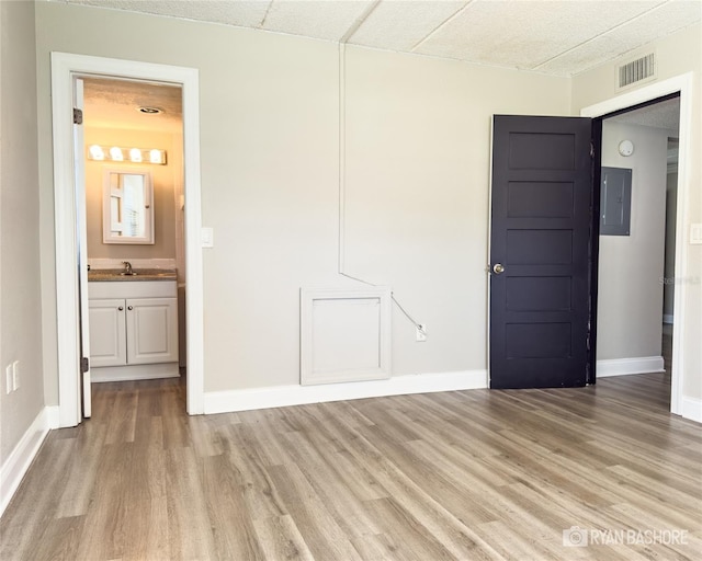 unfurnished room with sink, electric panel, and light wood-type flooring