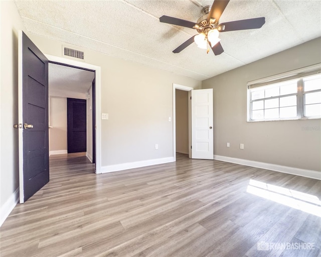 unfurnished bedroom featuring a textured ceiling, light wood-type flooring, and ceiling fan