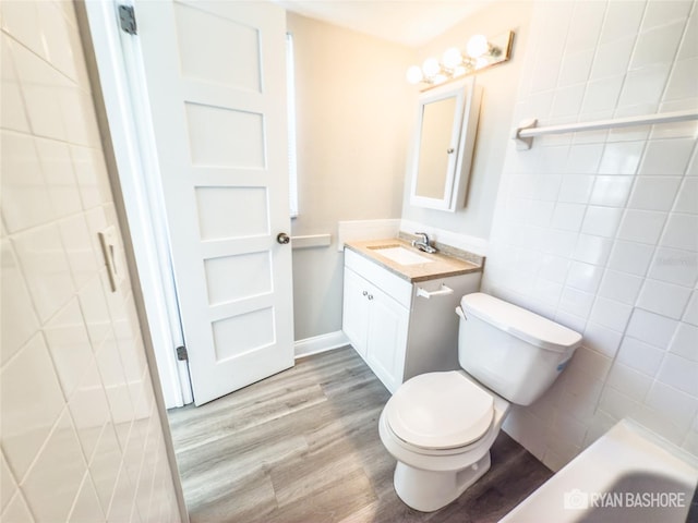 full bathroom featuring shower with separate bathtub, hardwood / wood-style floors, toilet, tile walls, and vanity