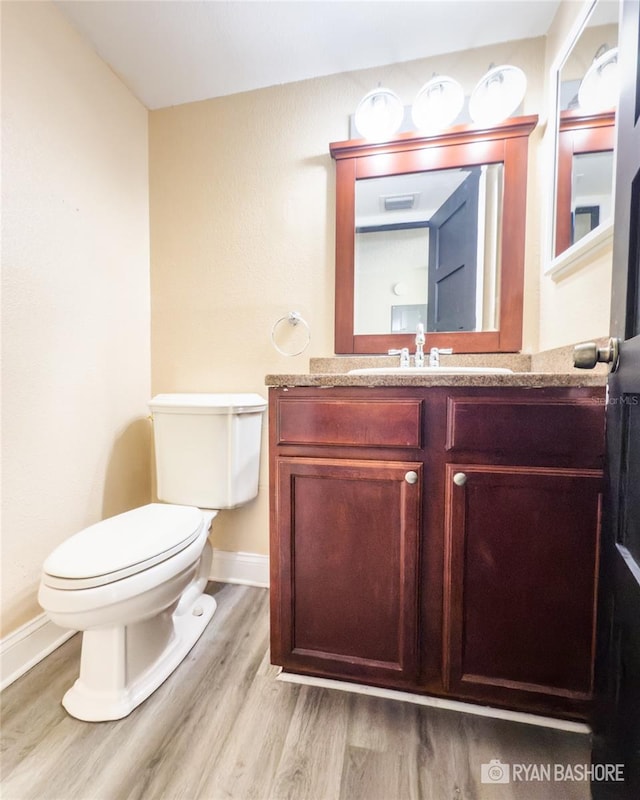 bathroom featuring vanity, hardwood / wood-style floors, and toilet