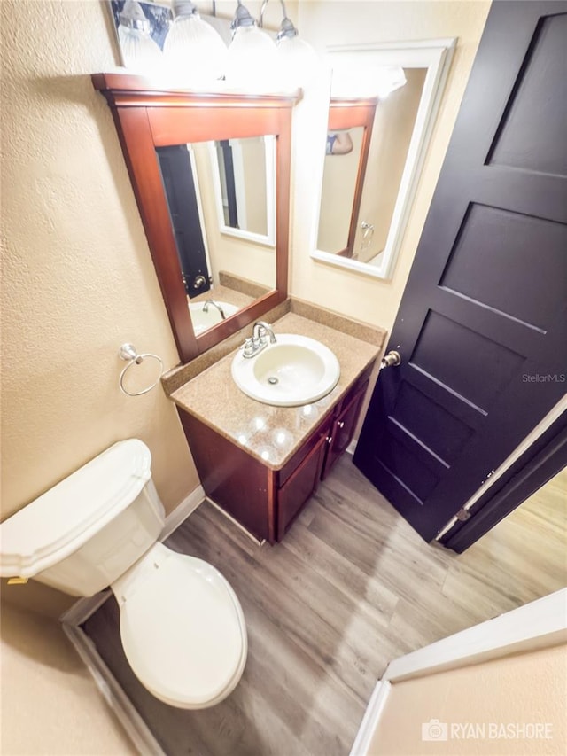 bathroom with vanity, toilet, and wood-type flooring