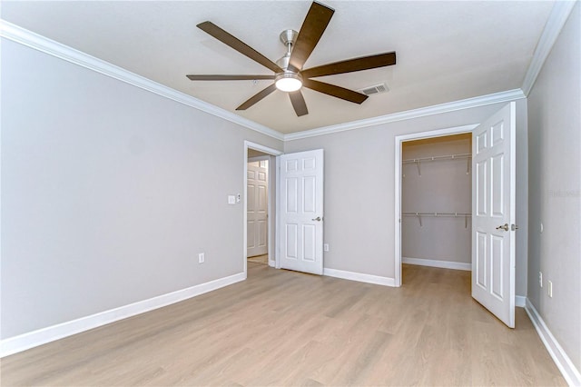 unfurnished bedroom with ornamental molding, light wood-type flooring, a spacious closet, and ceiling fan