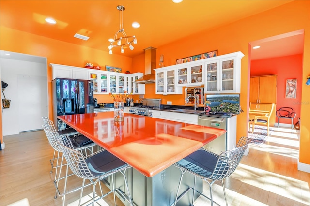 kitchen featuring sink, a breakfast bar area, light wood-type flooring, white cabinets, and pendant lighting