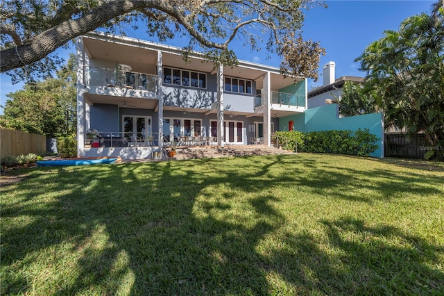 rear view of house featuring a lawn and a balcony