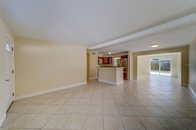 unfurnished living room with beam ceiling and light tile patterned floors