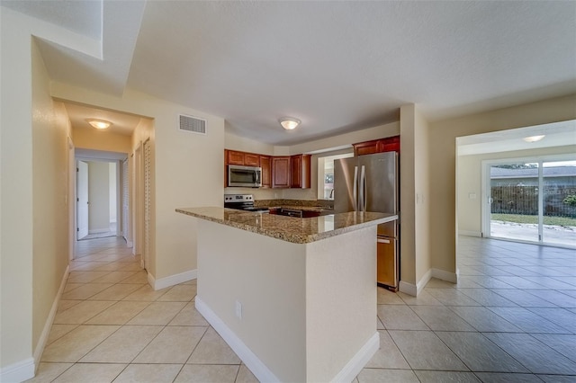 kitchen featuring sink, stone counters, light tile patterned floors, and appliances with stainless steel finishes