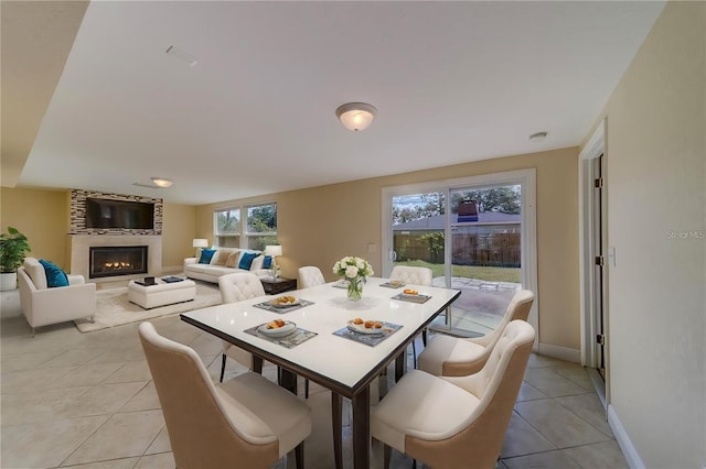 dining room featuring light tile patterned flooring and a large fireplace