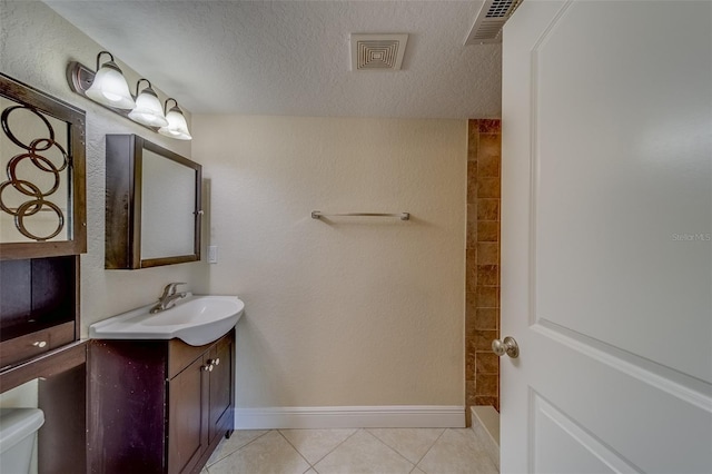 bathroom featuring vanity, a textured ceiling, tile patterned floors, and toilet