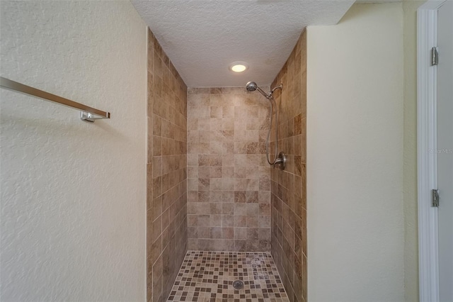 bathroom featuring a textured ceiling and a tile shower