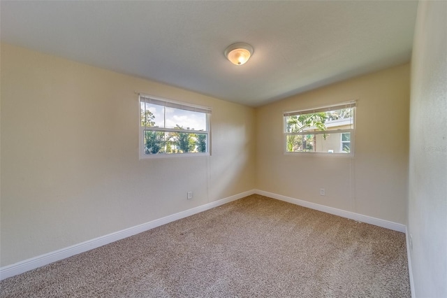 spare room featuring plenty of natural light, carpet floors, and vaulted ceiling