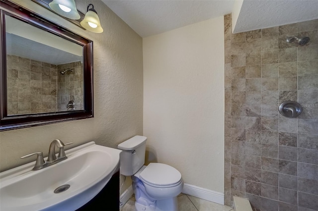 bathroom with a textured ceiling, tile patterned floors, a tile shower, and toilet