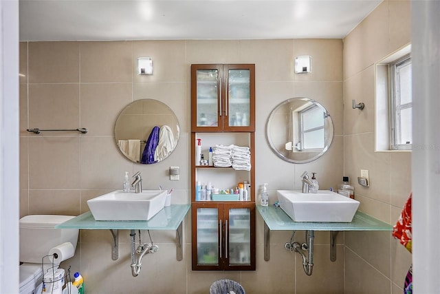 bathroom featuring sink, tile walls, and toilet