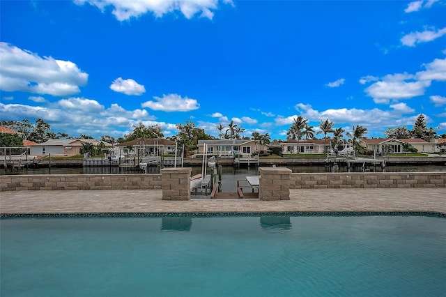 view of swimming pool with a dock, a water view, and a patio