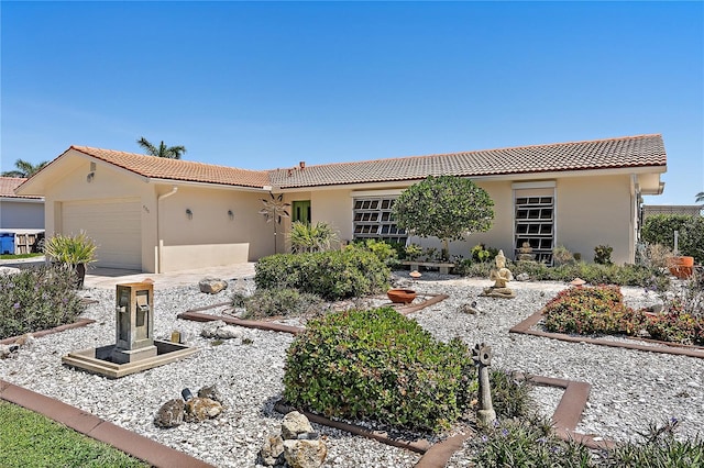 view of front facade with an attached garage, a tile roof, stucco siding, and driveway