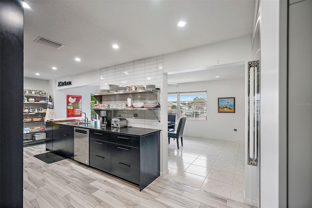 kitchen with a sink, dark cabinetry, modern cabinets, visible vents, and dark countertops