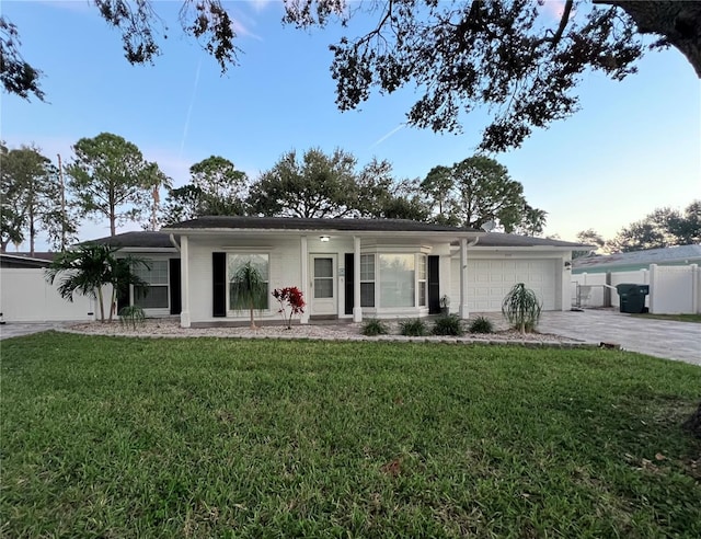 ranch-style home with a garage and a lawn