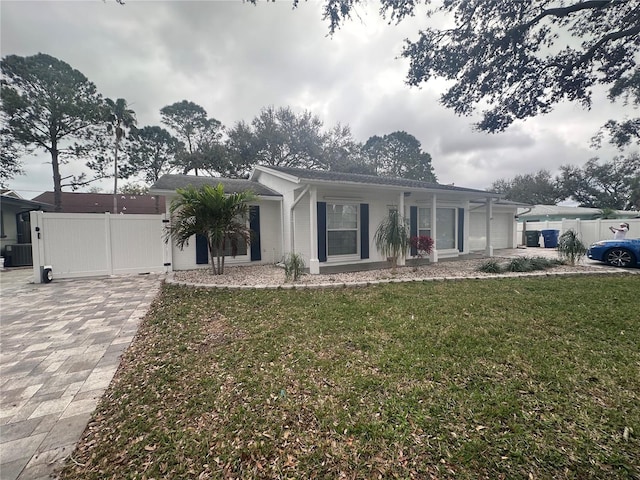 ranch-style house featuring a front yard, driveway, central AC unit, and fence