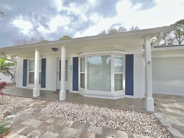 entrance to property with brick siding and an attached garage