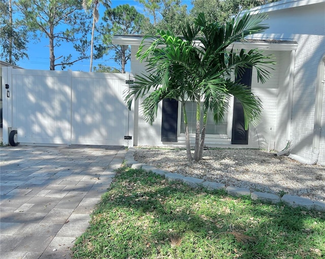 view of side of home featuring brick siding and a gate