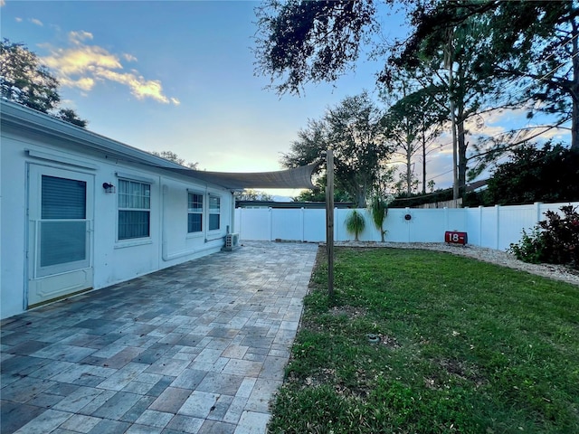 yard at dusk with a patio area and a fenced backyard