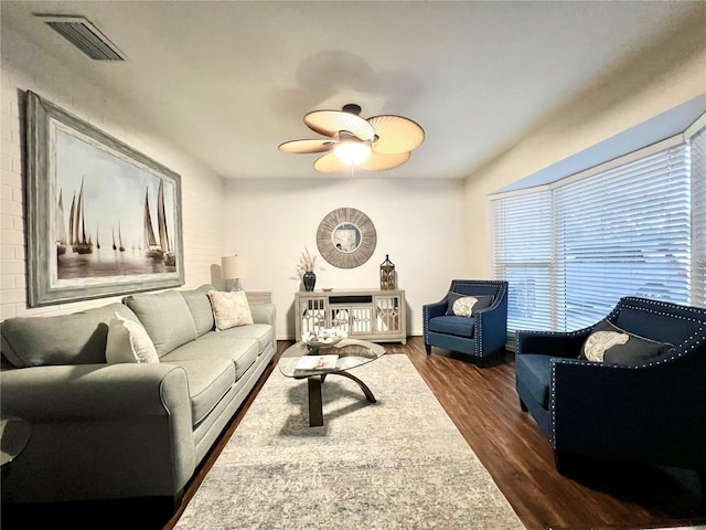 living area featuring dark wood-style flooring, visible vents, ceiling fan, and baseboards