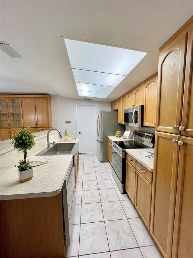 kitchen featuring stainless steel appliances, light countertops, visible vents, glass insert cabinets, and a sink