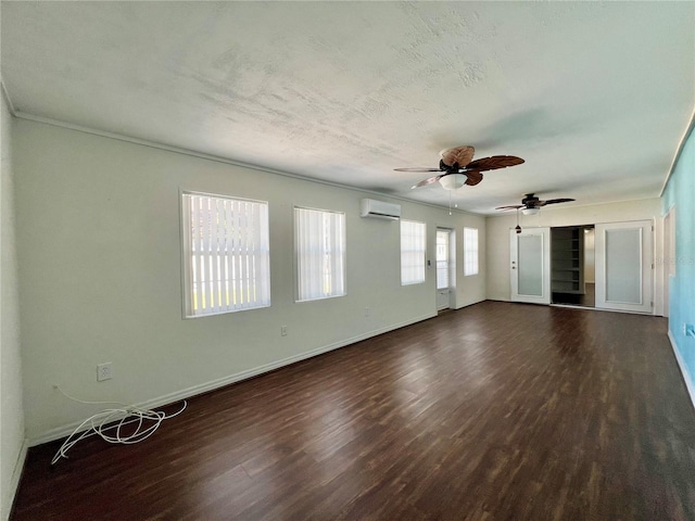 empty room with an AC wall unit, baseboards, a textured ceiling, and dark wood-style flooring