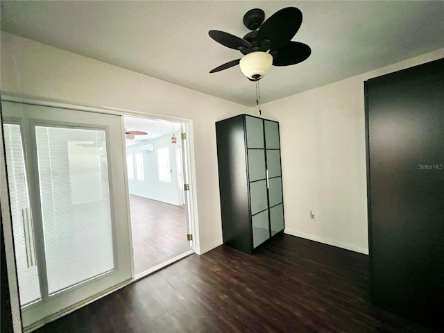 unfurnished room with a ceiling fan, dark wood-style flooring, and baseboards